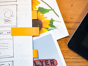 Creative workspace with sketches, sunflower photo, and smartphone
