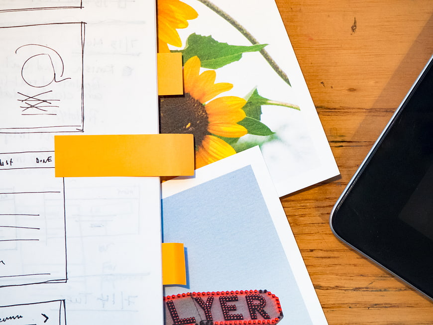 Creative workspace with sketches, sunflower photo, and smartphone