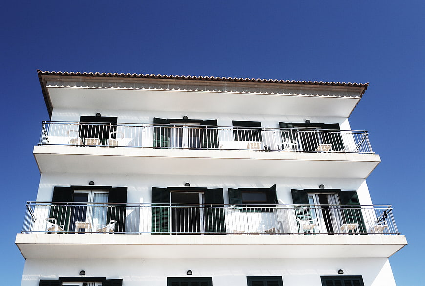 White Mediterranean Apartment Building with Balconies Against Blue Sky