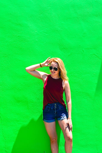 Happy Blonde Woman in Sunglasses Against Vibrant Green Wall