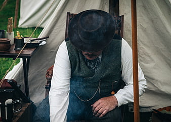 Man in vintage western attire sitting in a tent