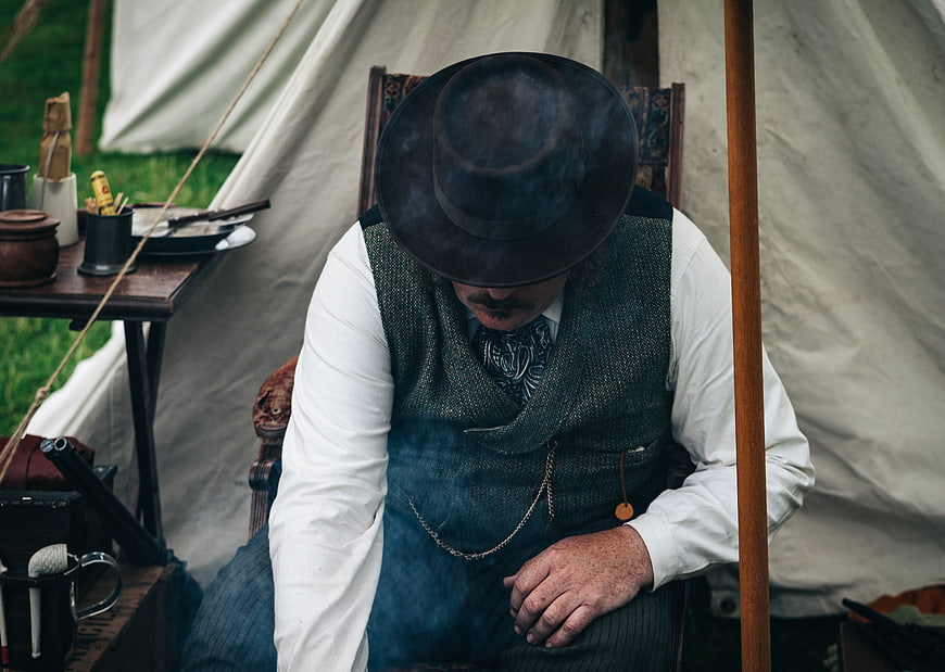 Man in vintage western attire sitting in a tent