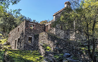 Ancient stone ruins with bell tower in a forested landscape