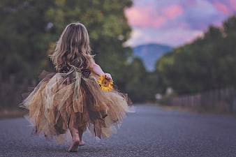 Little Girl Running Down Road with Sunflower at Sunset
