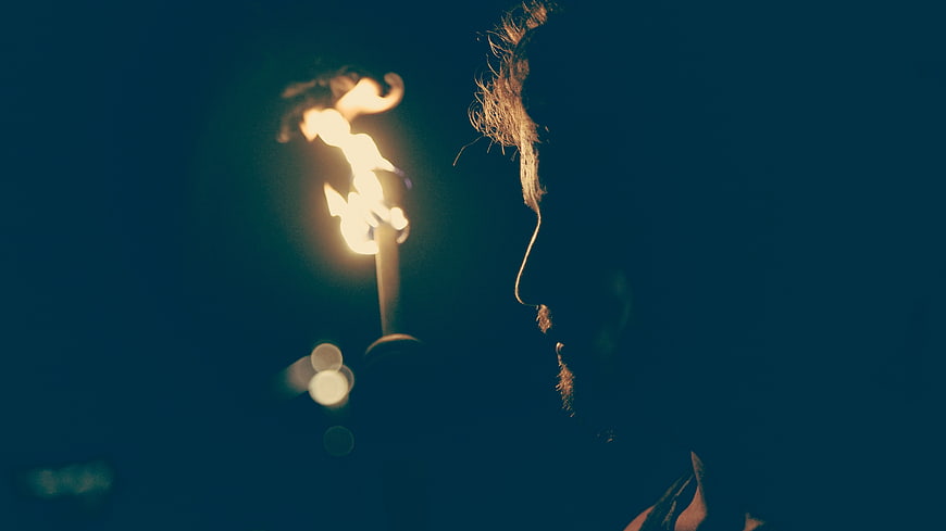 Man's Silhouette Profile Lit by Candle Flame in Dark Blue