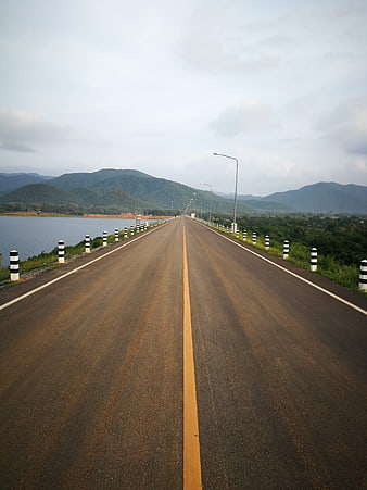 Empty asphalt road on dam bridge with mountains