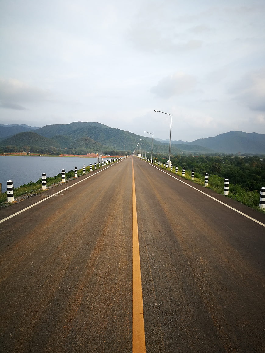 Empty asphalt road on dam bridge with mountains