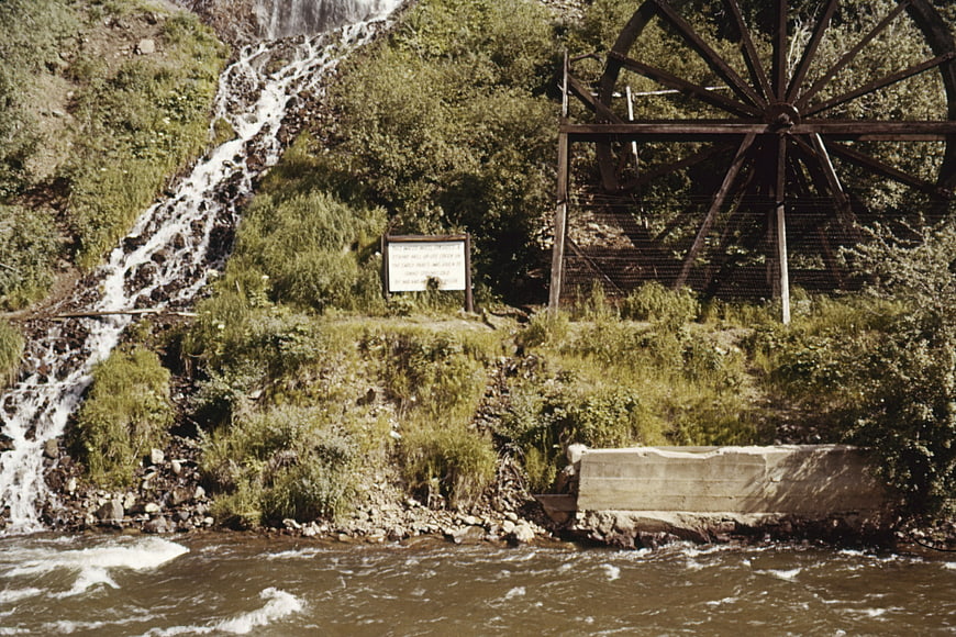 Vintage wooden water wheel by a rushing river stream