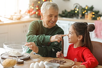 Grandmother and granddaughter baking cookies together in kitchen