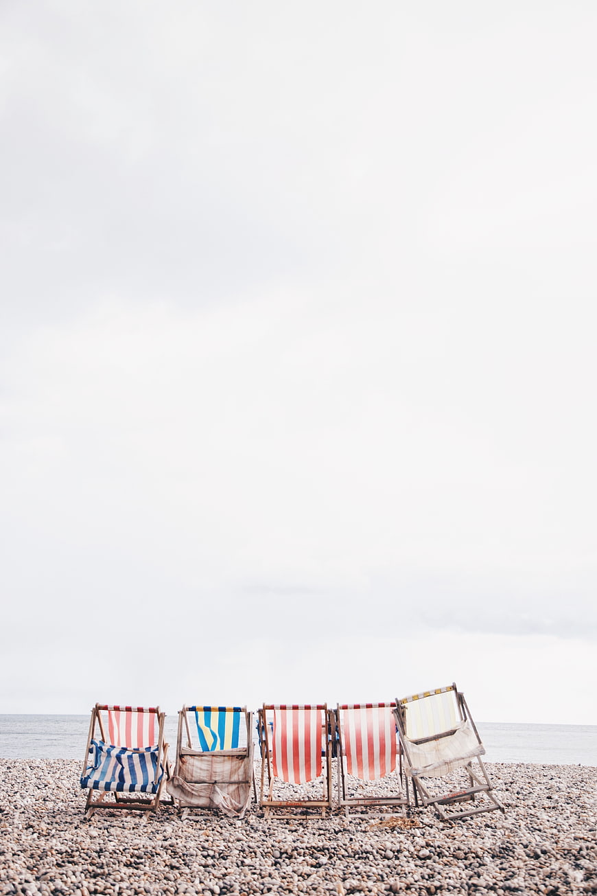 Striped Beach Chairs on Pebble Shore with Copyspace