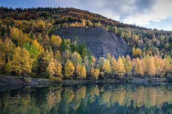 Autumn forest landscape with cliff and lake reflection