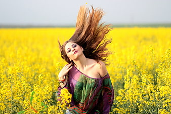 Woman with flowing hair in yellow flower field
