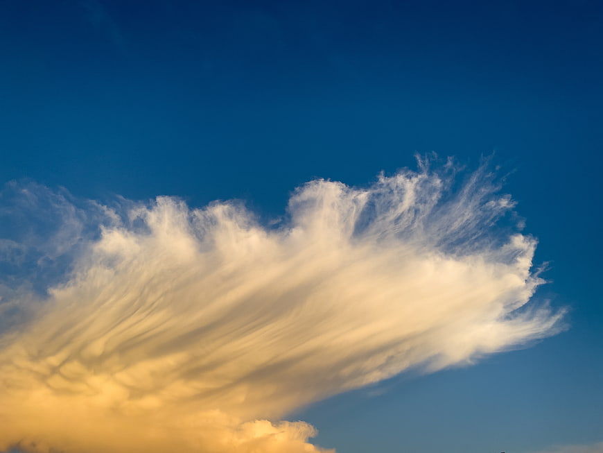 Golden Wispy Clouds Against Deep Blue Sky