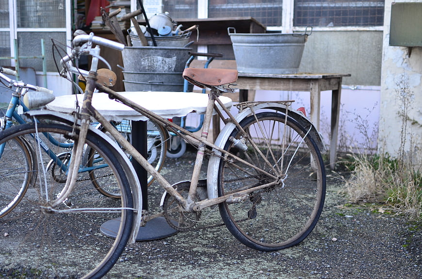 Rusty vintage bicycle in cluttered outdoor yard