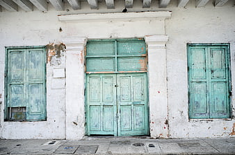 Weathered Turquoise Wooden Doors On White Colonial Facade