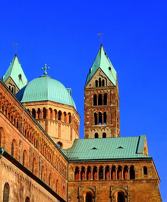 Red brick cathedral with green copper roofs against blue sky