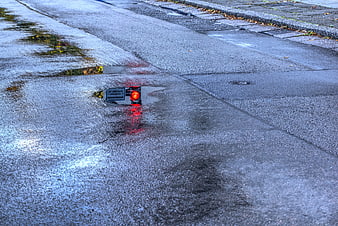 Red Traffic Light Reflection in Rainy Street Puddle