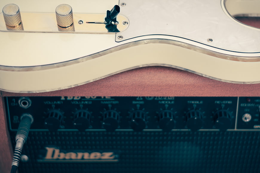 Close-up of white electric guitar resting on Ibanez amplifier