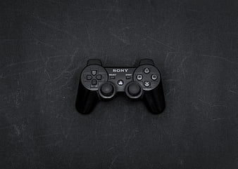 Black Sony PlayStation 2 Controller on Dark Textured Background