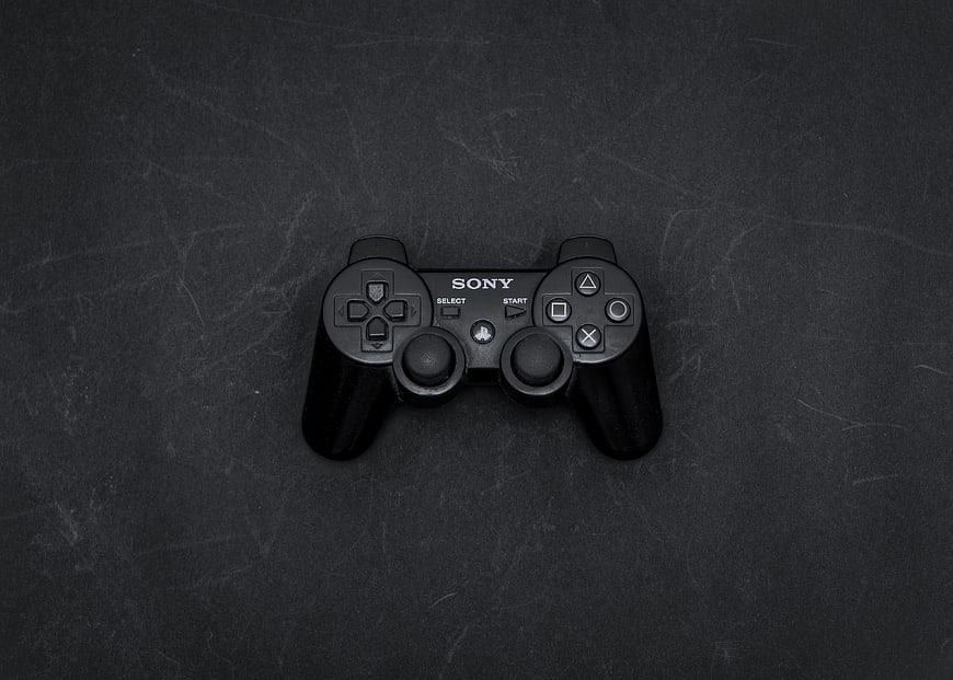 Black Sony PlayStation 2 Controller on Dark Textured Background