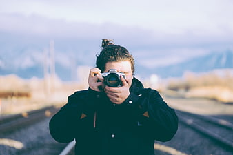 Man Taking Photo with Vintage Camera on Train Tracks