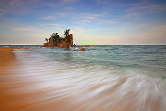 Long Exposure Serene Beach with Rocky Outcrop and Misty Waves