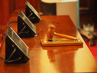 Wooden gavel and sound block on polished courtroom table