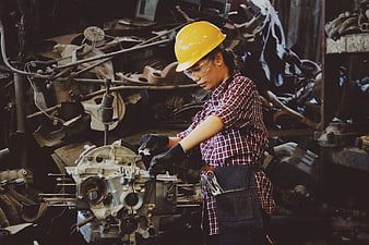 Female mechanic repairing engine in industrial workshop