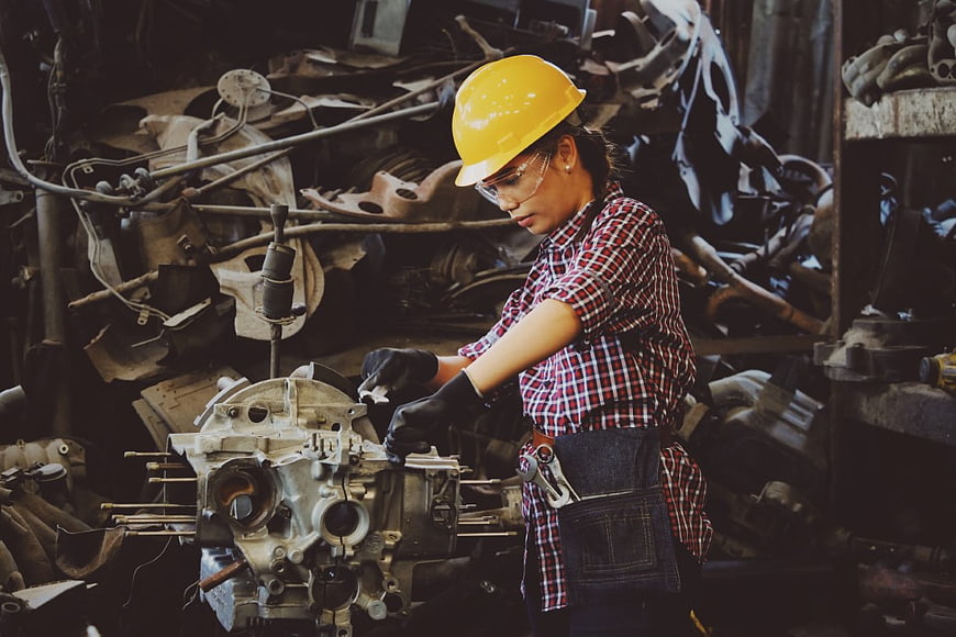 Female mechanic repairing engine in industrial workshop