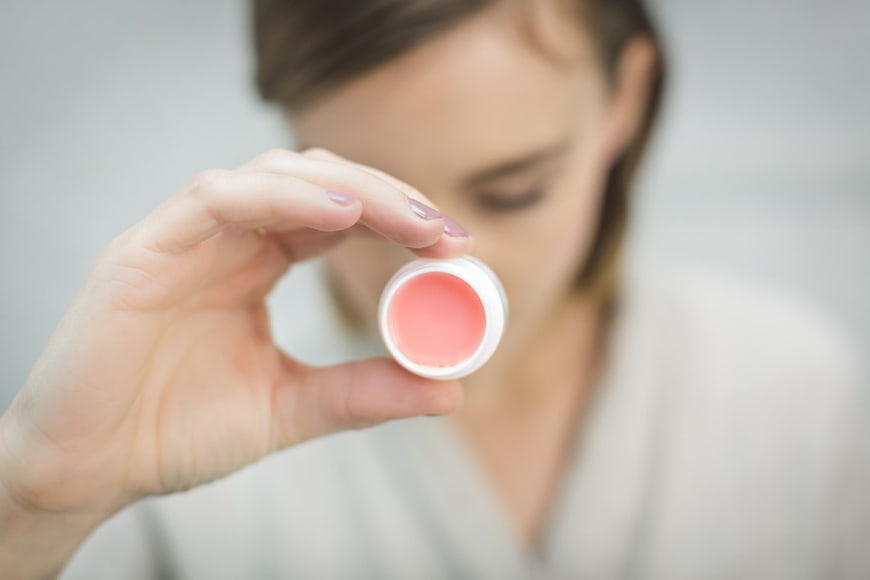 Woman holding pink lip balm close up