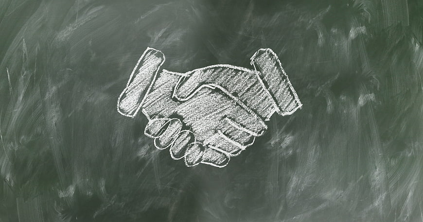 Chalk drawing of handshake on blackboard background