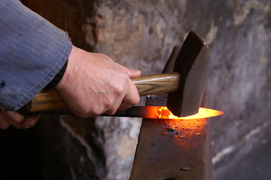 Blacksmith Forging Glowing Metal on Anvil