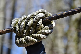 Close-up of a thick rope knot tied around a metal pole