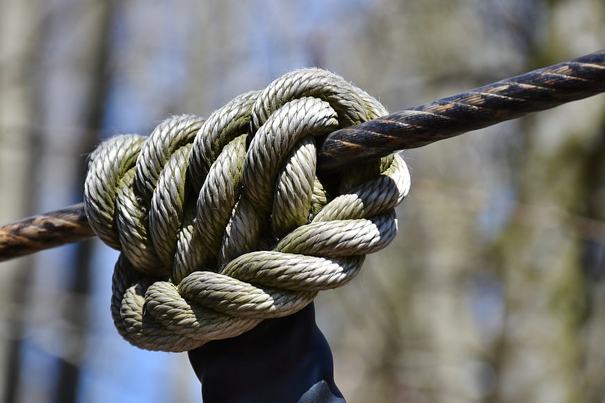 Close-up of a thick rope knot tied around a metal pole