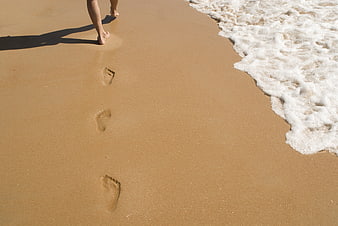 Footprints in wet sand near ocean waves