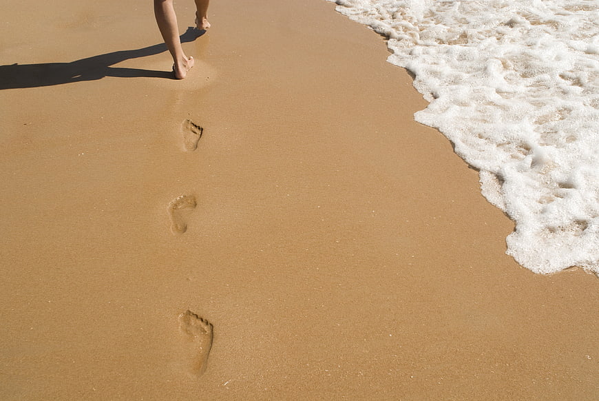 Footprints in wet sand near ocean waves