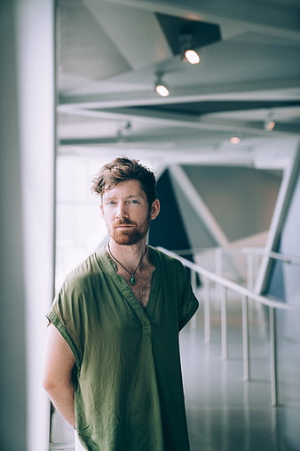 Portrait of a bearded man in a green shirt standing indoors
