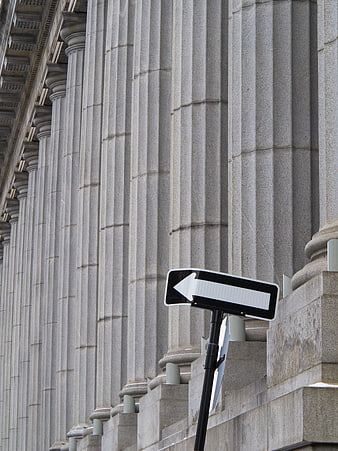Directional arrow sign in front of classical stone columns