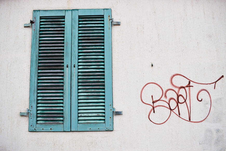 Vintage Teal Wooden Shutters on White Wall with Graffiti