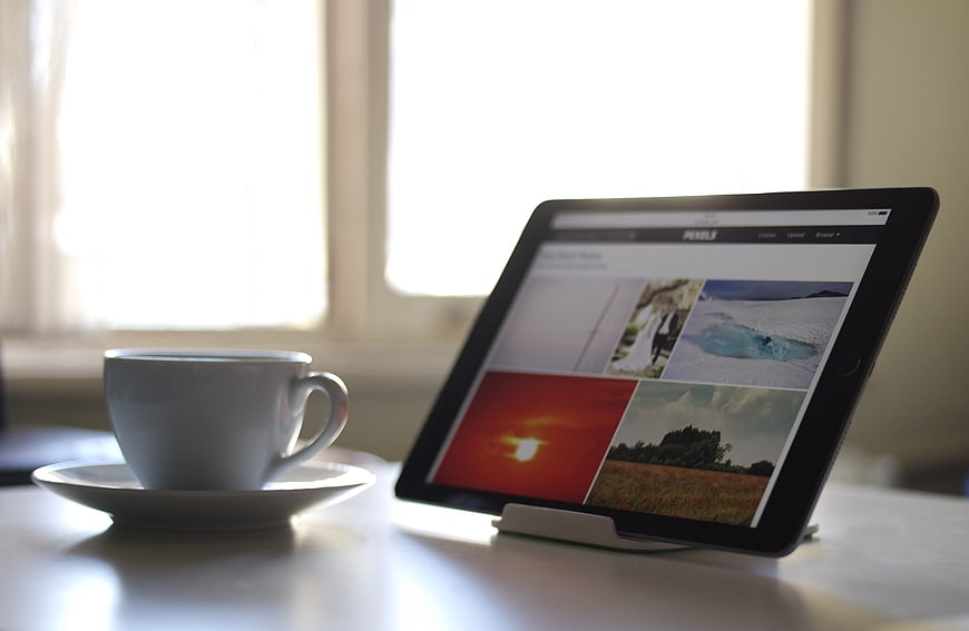 Tablet displaying photo website next to coffee cup