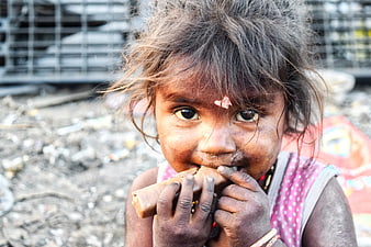Portrait of young Indian girl eating in slum