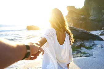 Couple holding hands walking on beach at sunset