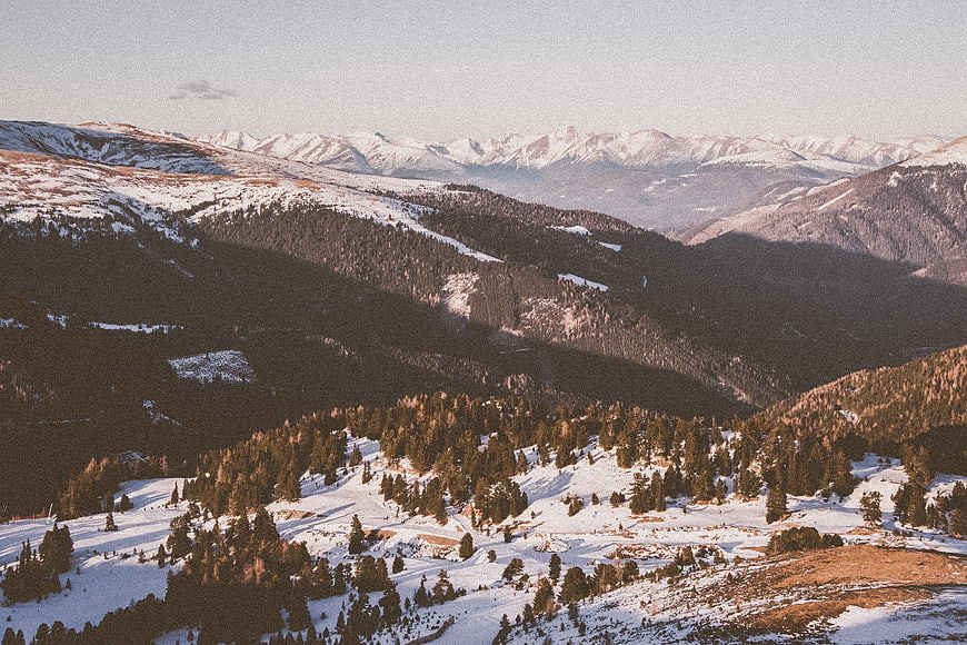 Snowy Mountain Landscape with Pine Forests and Distant Peaks