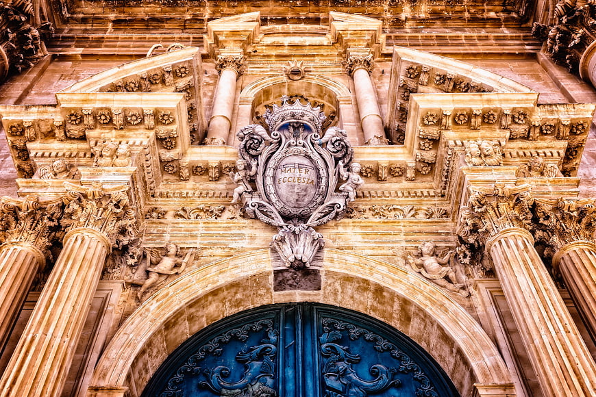 Ornate Baroque Church Facade with Blue Door and Stone Carvings