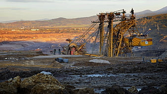 Large yellow mining excavator in open-pit coal mine at sunset