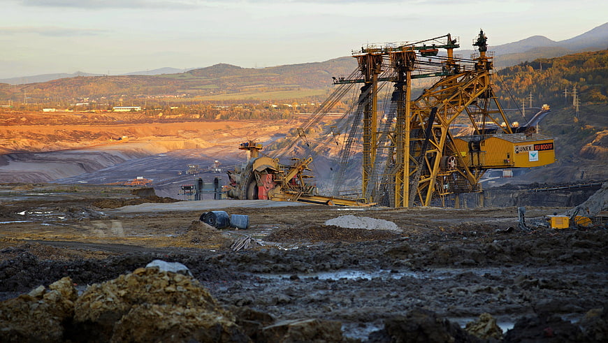 Large yellow mining excavator in open-pit coal mine at sunset