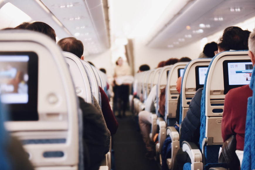 Passengers seated in airplane cabin aisle view
