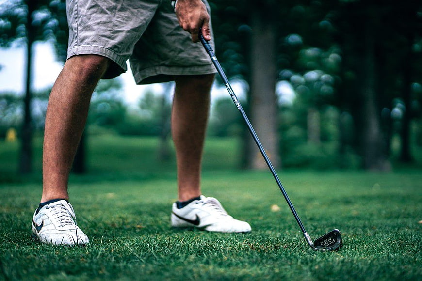 Golfer's legs and golf club on green grass