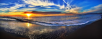 Panoramic sunset over ocean waves on sandy beach