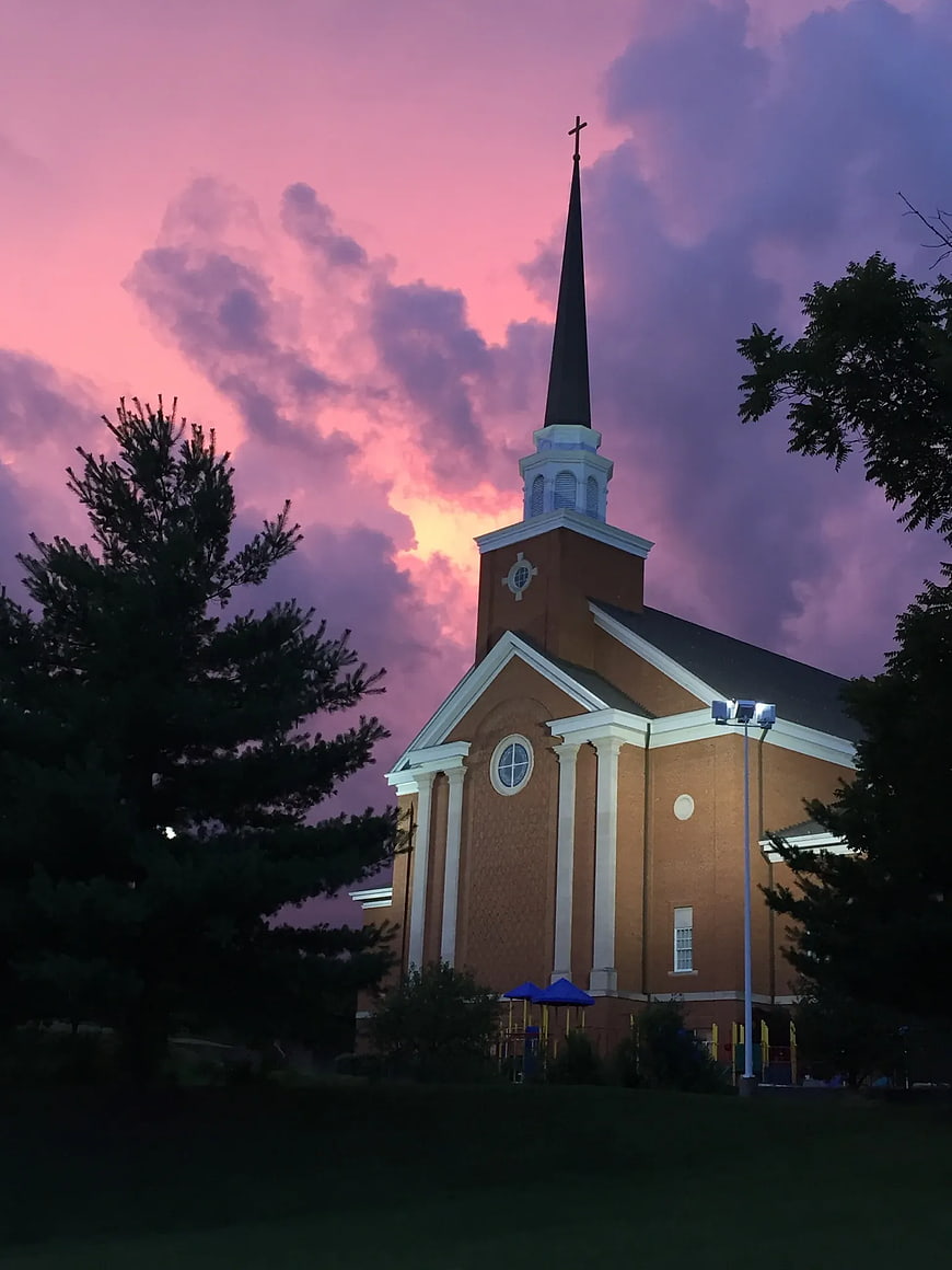 Brick Church with Steeple Against Dramatic Pink Sunset Sky